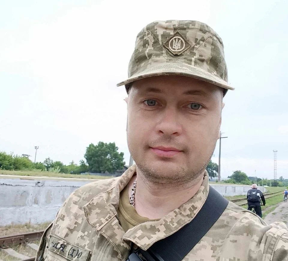 Арсенал пам'яті: як зберігають спадщину артилериста Дмитра Кузнецова 7 Чоловік у камуфляжній формі дивиться в об’єктив біля залізничних колій. Позаду нього двоє людей ідуть уздовж колії.
